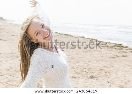 Young blonde carefree woman with arms outstretched on Atlantic beach in Prince Edward Island, Canada