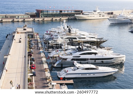 MONTE CARLO, MONACO - OCTOBER 3, 2014: Luxury yachts docked at pier of port Hercule in Monaco viewed from seaside gardens near casino.
