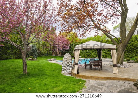 Residential  backyard with gazebo, deck, stone patio and swimming pool