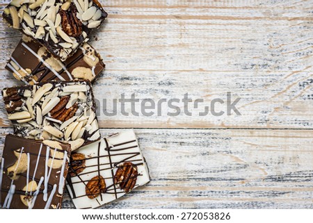 Assorted chocolate caramel bark pieces arranged on wooden background from above with copy space