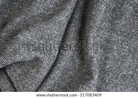 Draped herringbone tweed background with closeup on wool fabric texture