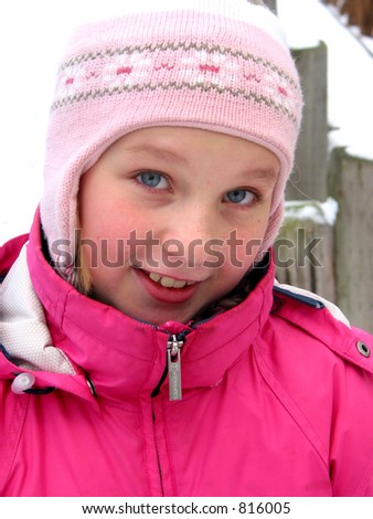 Portrait of a young girl in winter hat outside, snow in the background