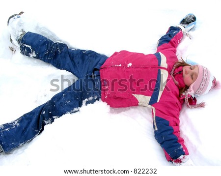 Winter fun: young girl making a snow angel on fresh white snow
