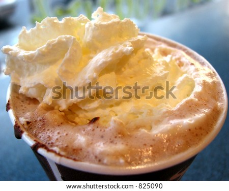 Hot chocolate with whipped cream in a paper cup, closeup