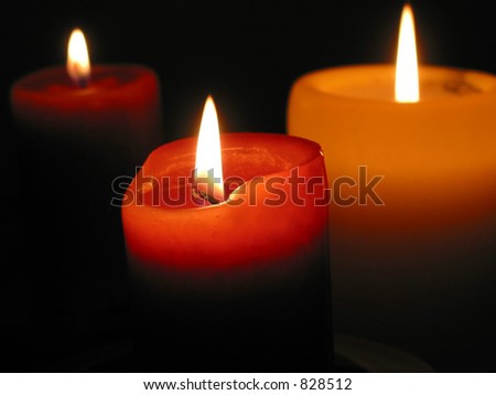 Three candles burning in the dark, focus on the front candle