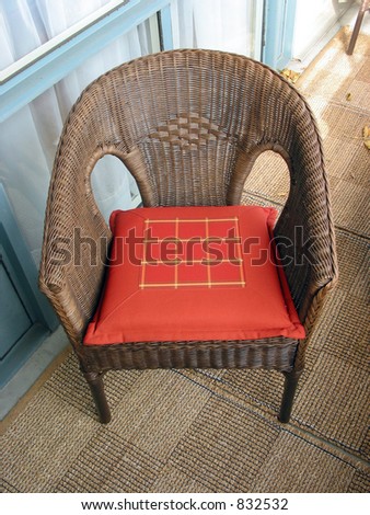 Brown wicker chair with red cushion