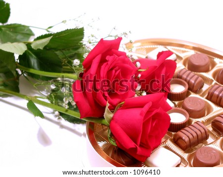 Red roses with heart shaped box of chocolates on white background