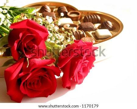 Red roses with heart-shaped box of chocolates on white background
