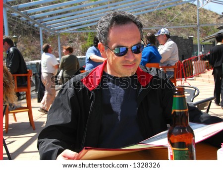 Man sitting on a restaurant patio reading menu