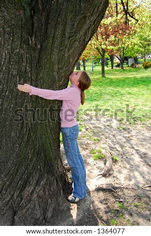 Young girl standing near ancient big tree. Protect environment concept.