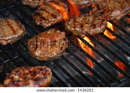 Hamburgers cooking on barbeque grill with flames Hamburgers cooking on barbeque grill with flames