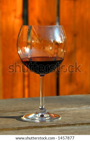 Glass of red wine on old rustic table, vertical