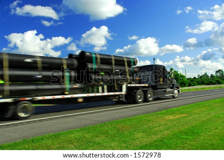 Fast moving truck on highway delivering pipes, blurred because of fast motion