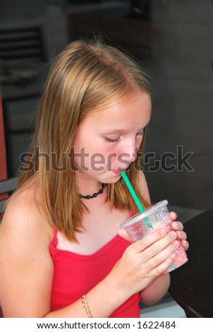 Young girl sitting in outside cafe and drinking a cool refreshing beverage