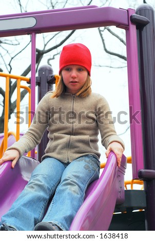 Young girl on a playground, about to go down the slides