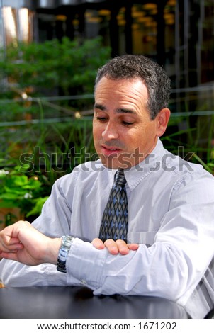 Businessman looking at his wrist watch expressing frustration