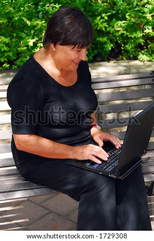 Mature woman typing on portable computer outdoor