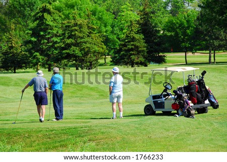 Three senior men on golf course with a golf cart