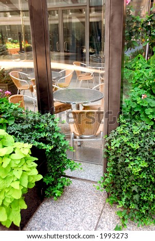 Restaurant outdoor patio behind glass walls with green plants