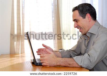 Man sitting at a desk and looking into his computer showing happiness and excitement