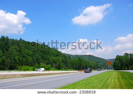 Divided highway among green hills on sunny summer day
