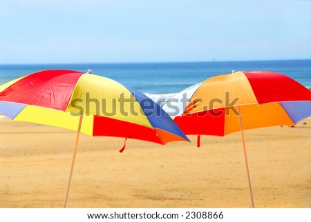 Two beach umbrella standing on ocean shore