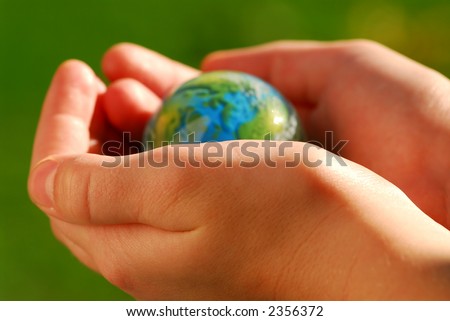 Child\'s hands holding a globe on green background