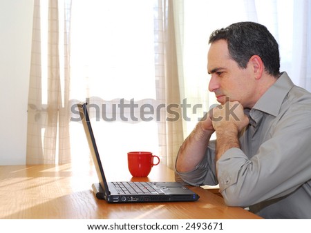 Man sitting at his desk with a laptop looking concerned