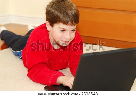 Young boy lying on the floor with portable computer