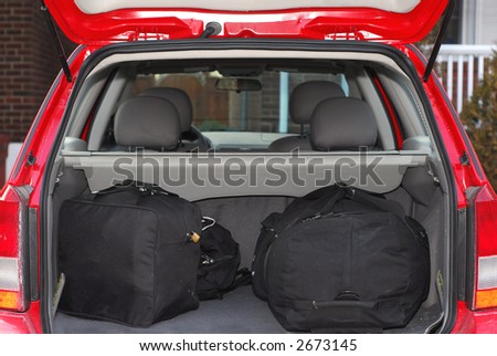 Red hatchback car loaded with open trunk and luggage