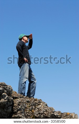 A man standing on top of a cliff looking into the distance