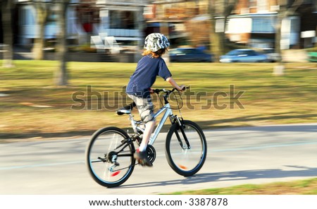 stock photo Panning shot of a boy riding a bicycle motion blurred