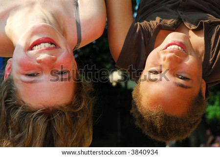 Two girls hanging upside down in a playground