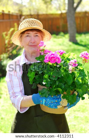 Senior woman holding a pot with flowers in her garden, shallow dof, focus on flowers