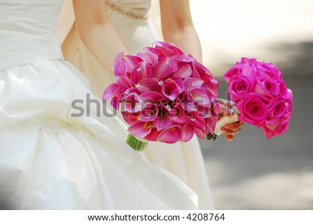 Bride and bridesmaid holding bouquets of pink flowers