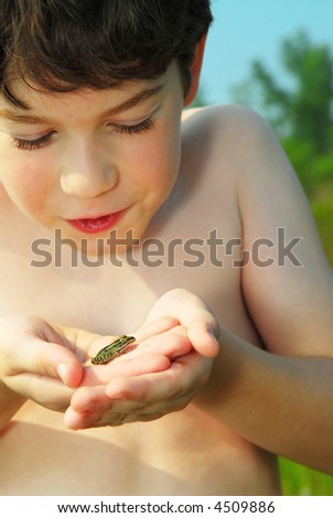 stock photo Young boy holding a tiny green frog in his hands