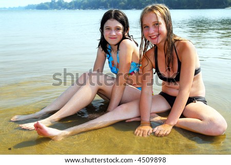 stock photo Two preteen girls sitting in shallow water on a beach