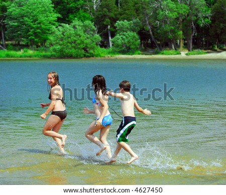 Group of children running into clear lake water