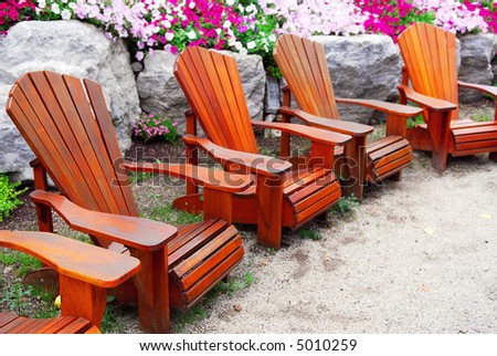 Row of solid wood patio chairs and natural stone landscaping