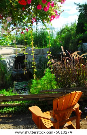 Natural stone pond and patio landscaping with wooden chair
