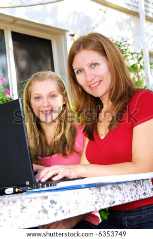 Mother and daughter working on a portable computer at home in the garden