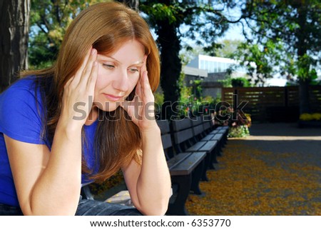 Mature woman with a headache sitting on the park bench