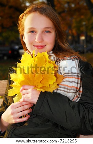 Portrait of a beautiful teenage girl with yellow fall maple leaves