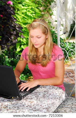 Teenage girl typing on a portable computer outside