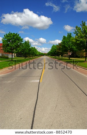 Empty residential street in suburban neighborhood lined with trees