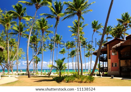 Luxury hotel at tropical resort on ocean shore with palm trees