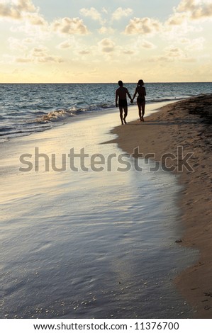Couple taking a walk on a sandy beach of tropical resort