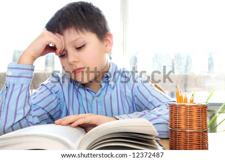 Serious school boy studying with a book