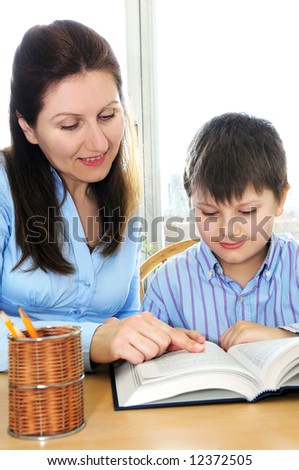 Teacher or tutor helping school boy to study