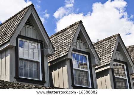 Window dormers on a house with wooden shingles on blue sky background